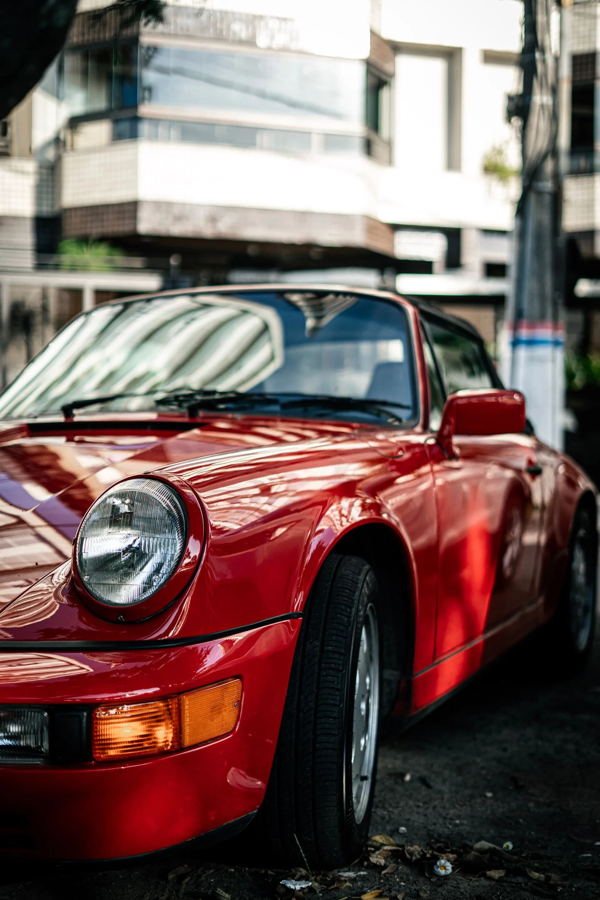 911 classique rouge de trois quarts avant, phare rond et chromes au soleil