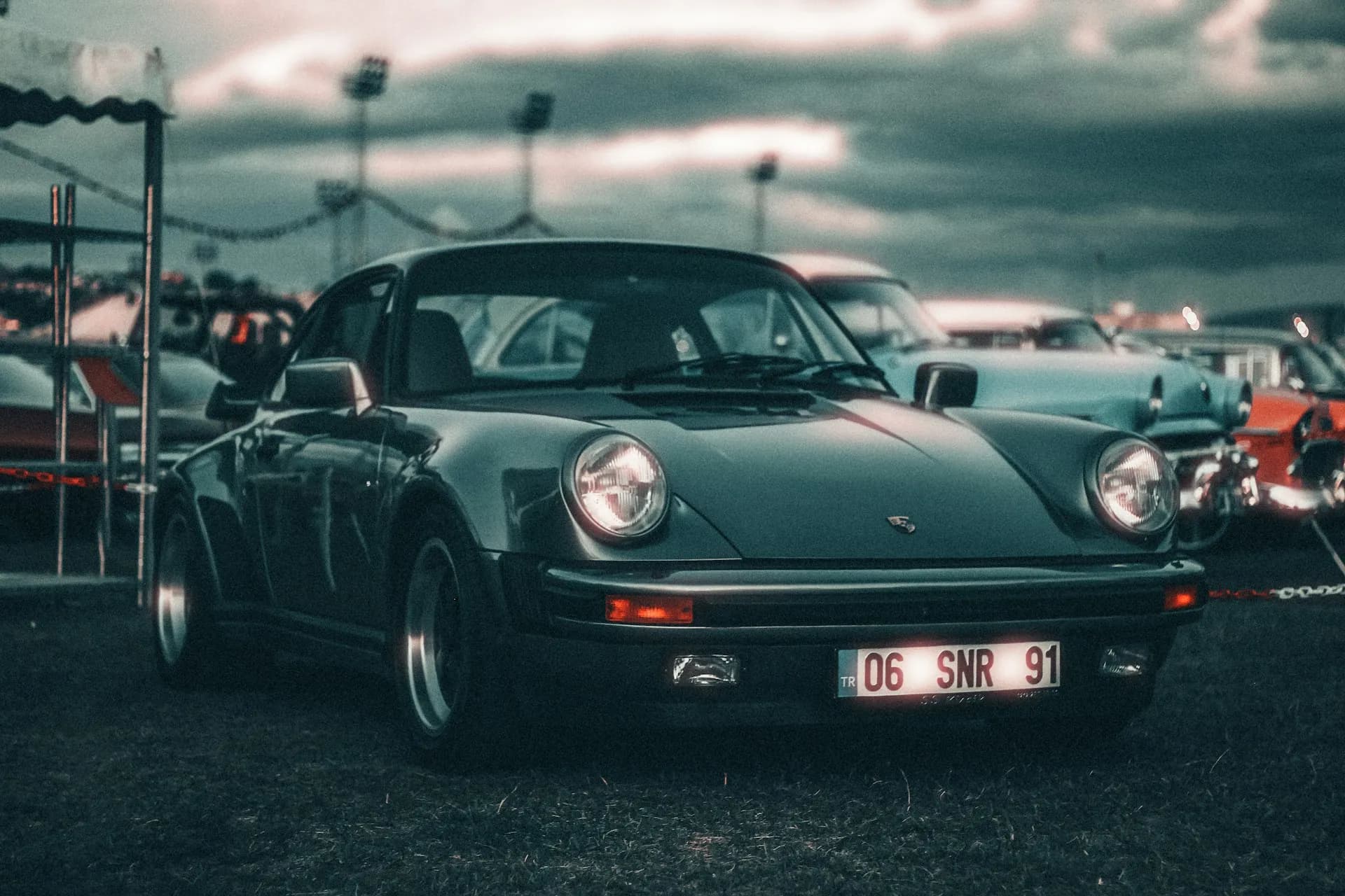 930 Turbo sombre à l'aileron caractéristique, trois quarts avant sous un ciel d'orage